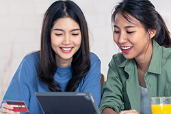 two women with debit card and computer